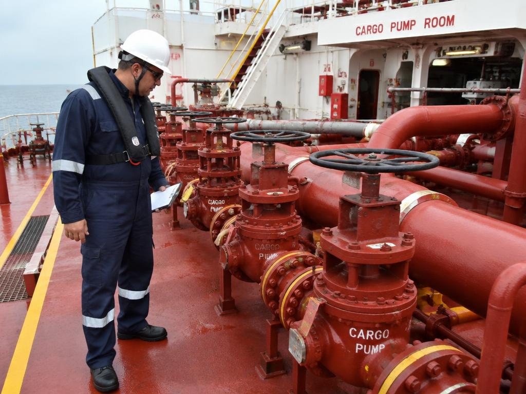 Inspector checking cargo pipelines and pumps on a tanker